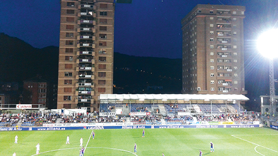 De to boligblokkene ruver over stadion. På hver veranda henger et SD Eibar-flagg, men også et banner i protest mot stadionutvidelsen.